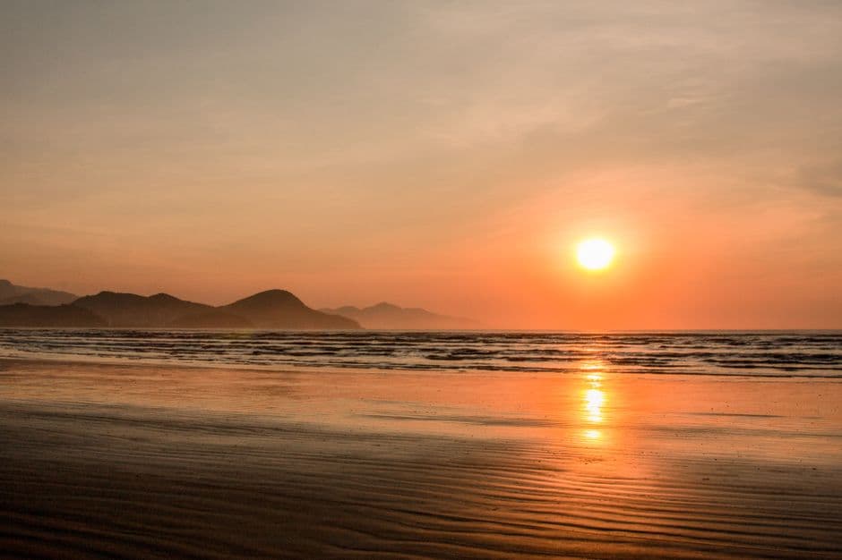 Playa de arena dorada, palmeras y cielo rojo al atardecer, en el chat de Caraguatatuba