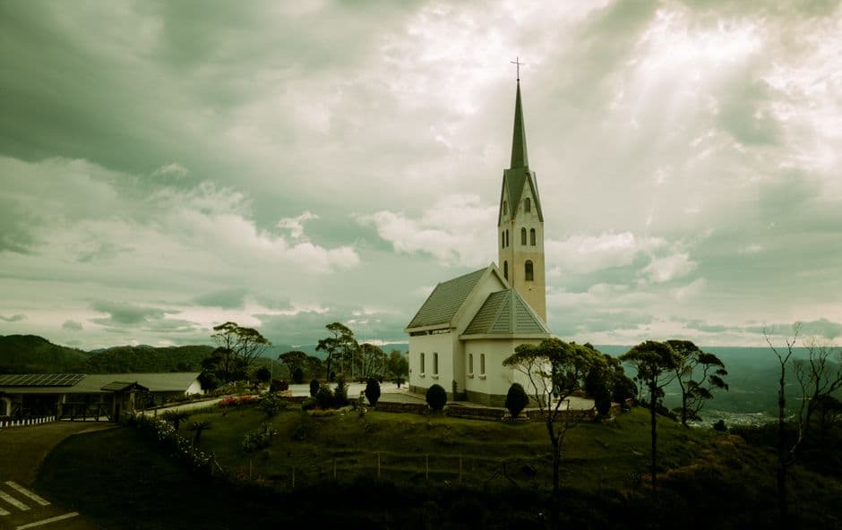 Iglesia blanca sobre cumbre montañosa bajo cielo claro, en el chat de Santa Cruz do Sul