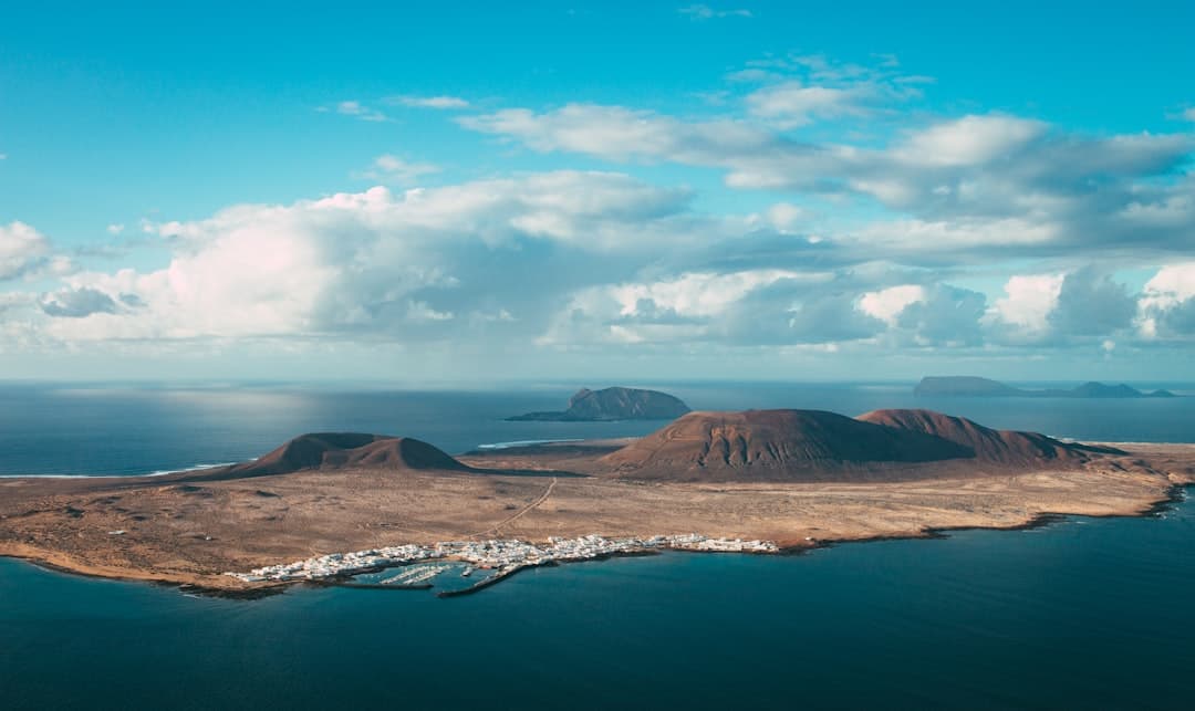 Montaña marrón junto a agua bajo cielo azul en la sala de chat de Canarias