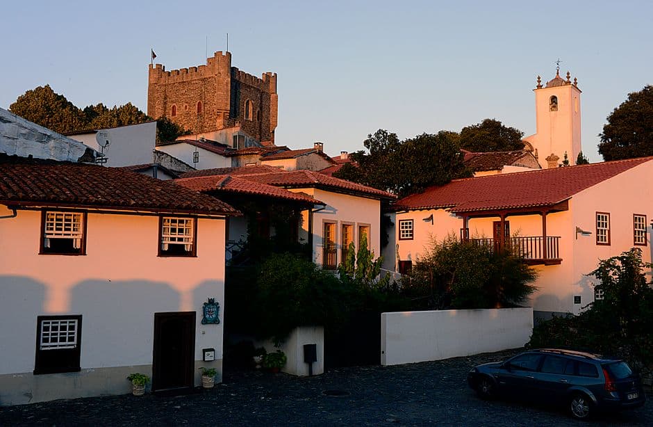 Casas coloridas alineadas bajo cielo azul, en el chat de Bragança