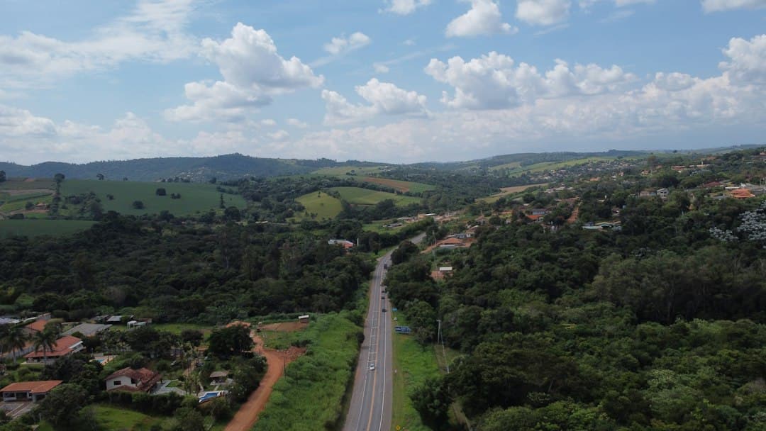 Vista aérea de una carretera flanqueada por árboles verdes, en la sala de chat de Itatiba