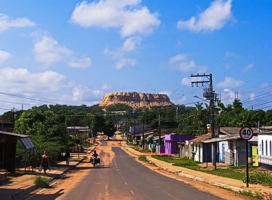 Carretera rural que atraviesa un pueblo hacia una montaña al fondo, en el chat de Guaratinguetá