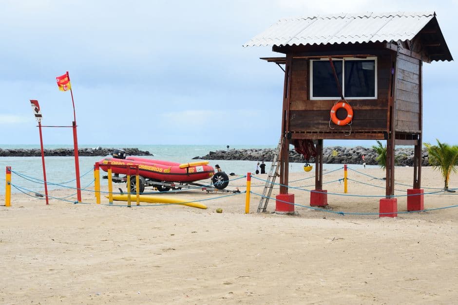 Estación de salvavidas colorida sobre la arena con vista al mar, en el chat de Marituba