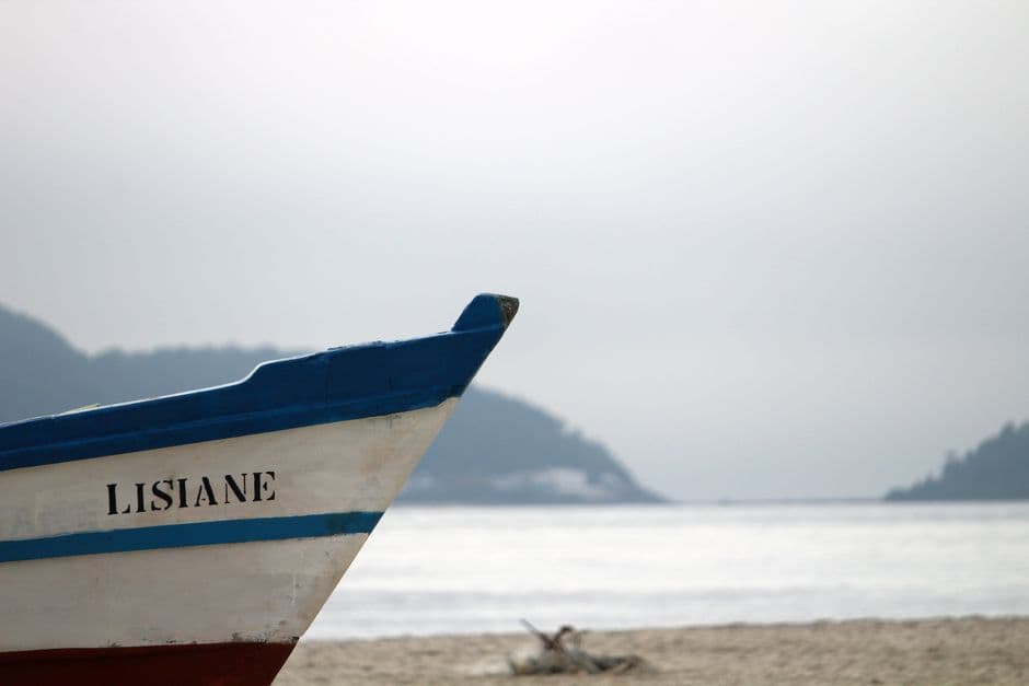 Barco de pesca anclado en la costa brasileña bajo cielo azul, en el chat de Guaianases