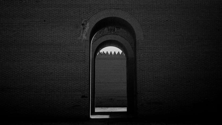 Pasaje arqueado entre muros de ladrillo, con luces tenues, en el chat de Babylon