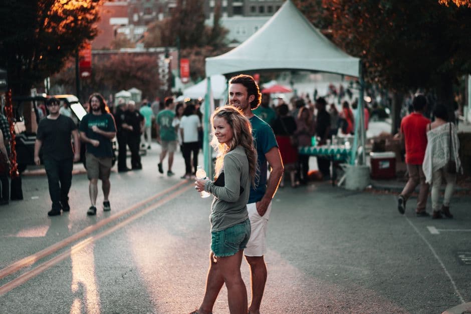 Pareja caminando entre gente en evento al aire libre, en la sala de chat de Fayetteville