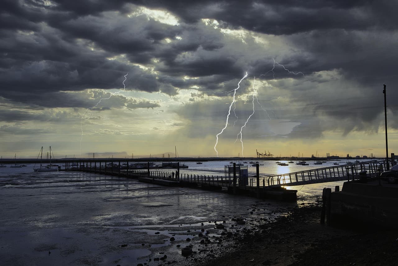 Muelle con barcos anclados y aguas bajo cielo nublado, en la sala de chat de Kent