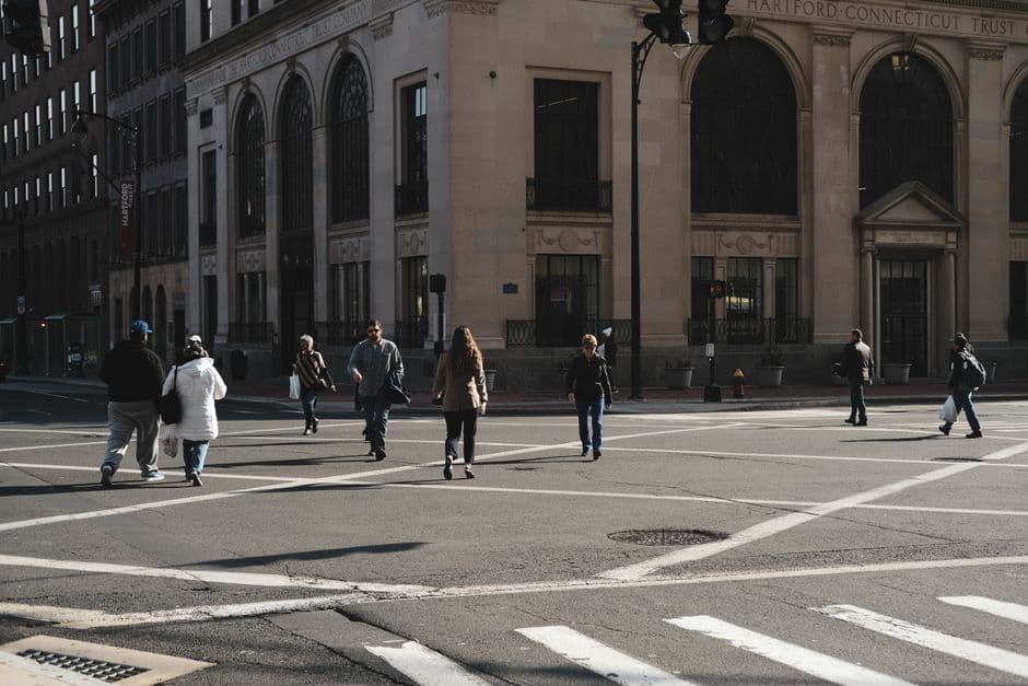 Personas cruzan la calle bajo semáforo en zona urbana, en la sala de chat de Hartford