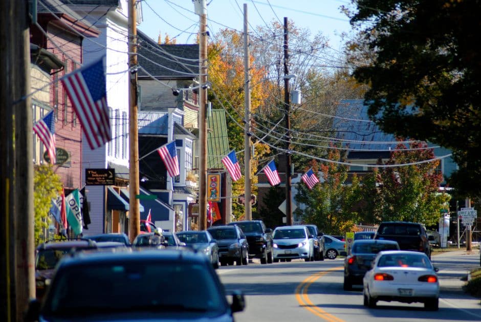 Calle transitada cruza barrio con casas y banderas estadounidenses, en la sala de chat de Smithtown