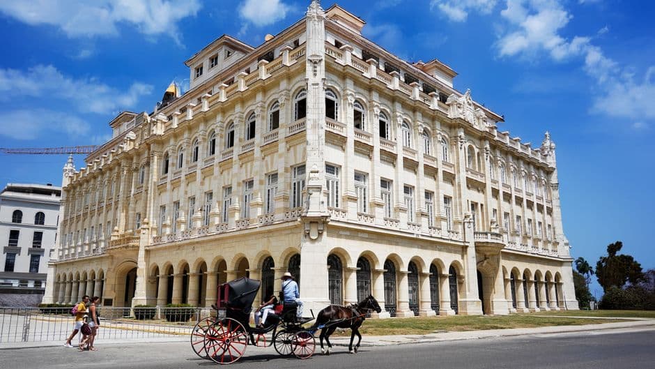 Elegante edificio colonial con un coche de caballos, en el chat de Habana del Este