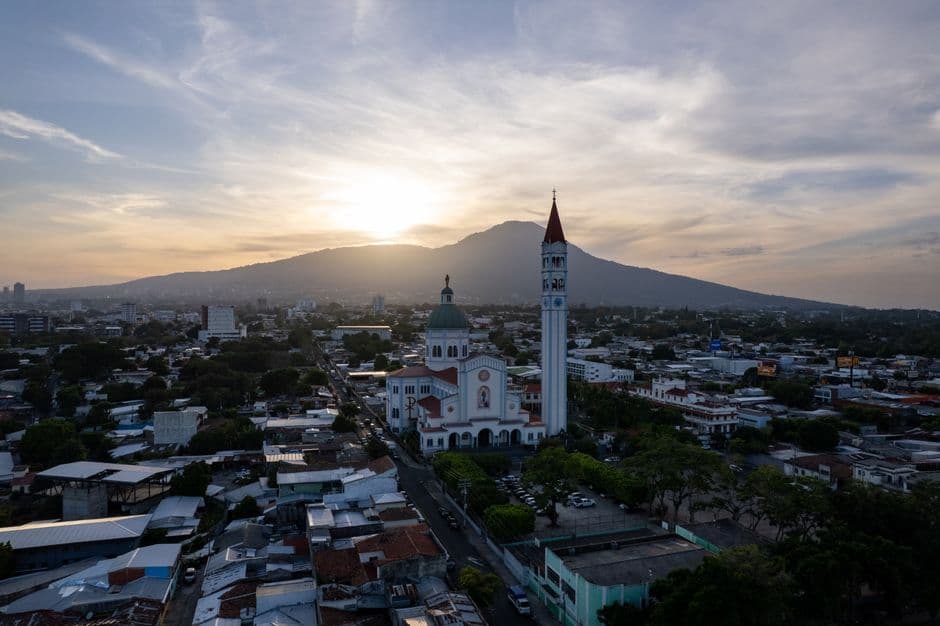 Vista aérea al atardecer de la ciudad y una basílica, en el chat de San Salvador Sur