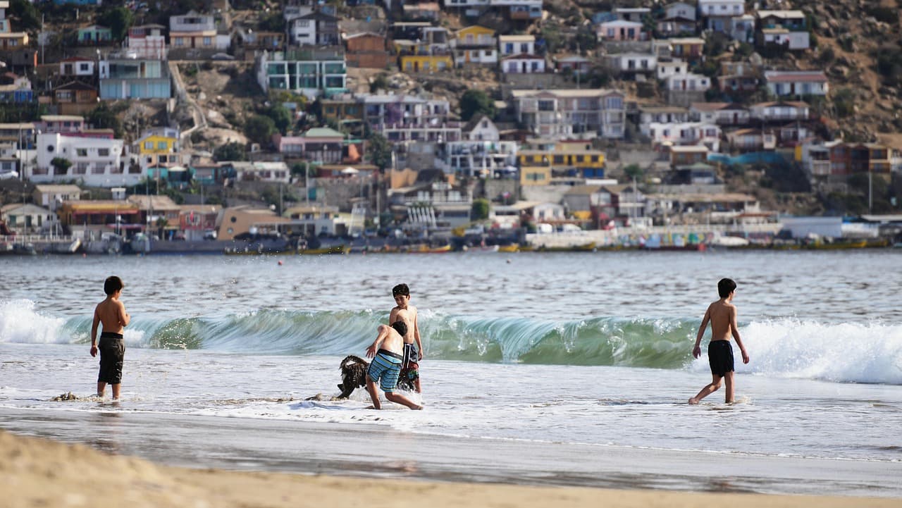 Personas jugando en la playa junto al mar, en el chat de Quilpué