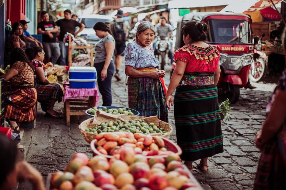 Mercado guatemalteco colorido con puestos de frutas y artesanías, en el chat de San Pedro Carchá