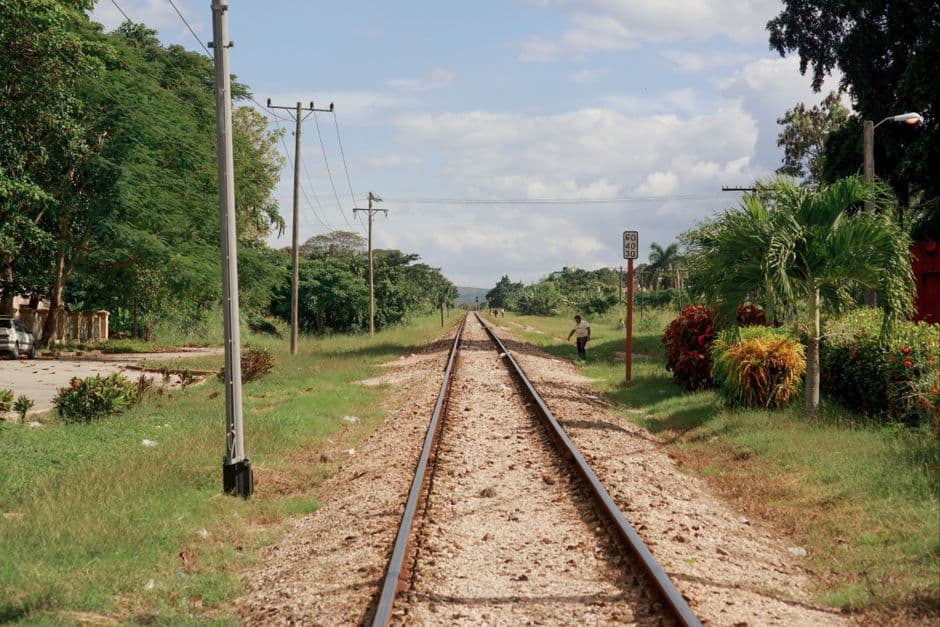 Vía de tren de color pardo junto a árboles verdes, en el chat de Jagüey Grande
