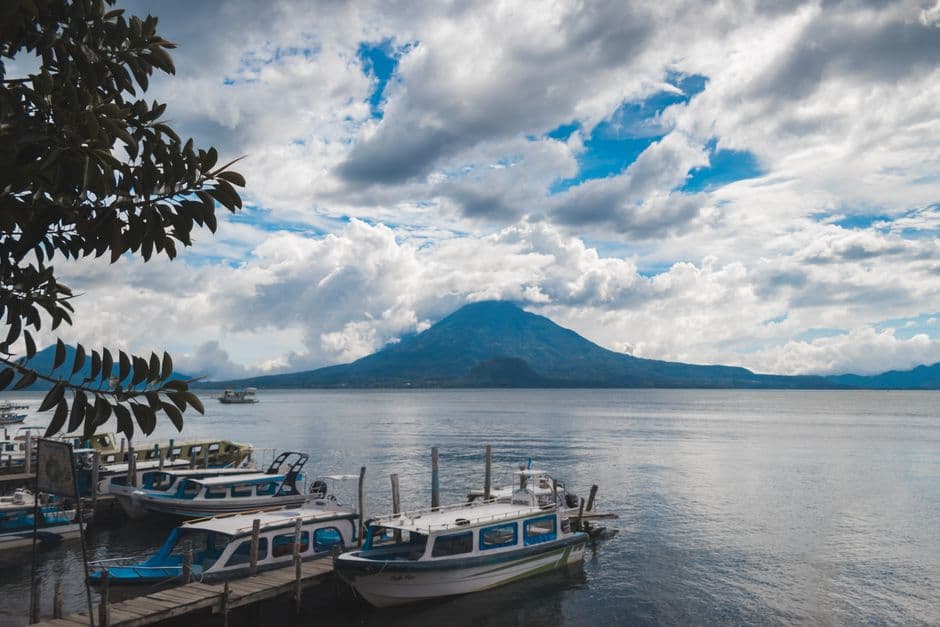 Barcas amarradas en un lago rodeado de montañas, en la sala de chat de Amatitlán