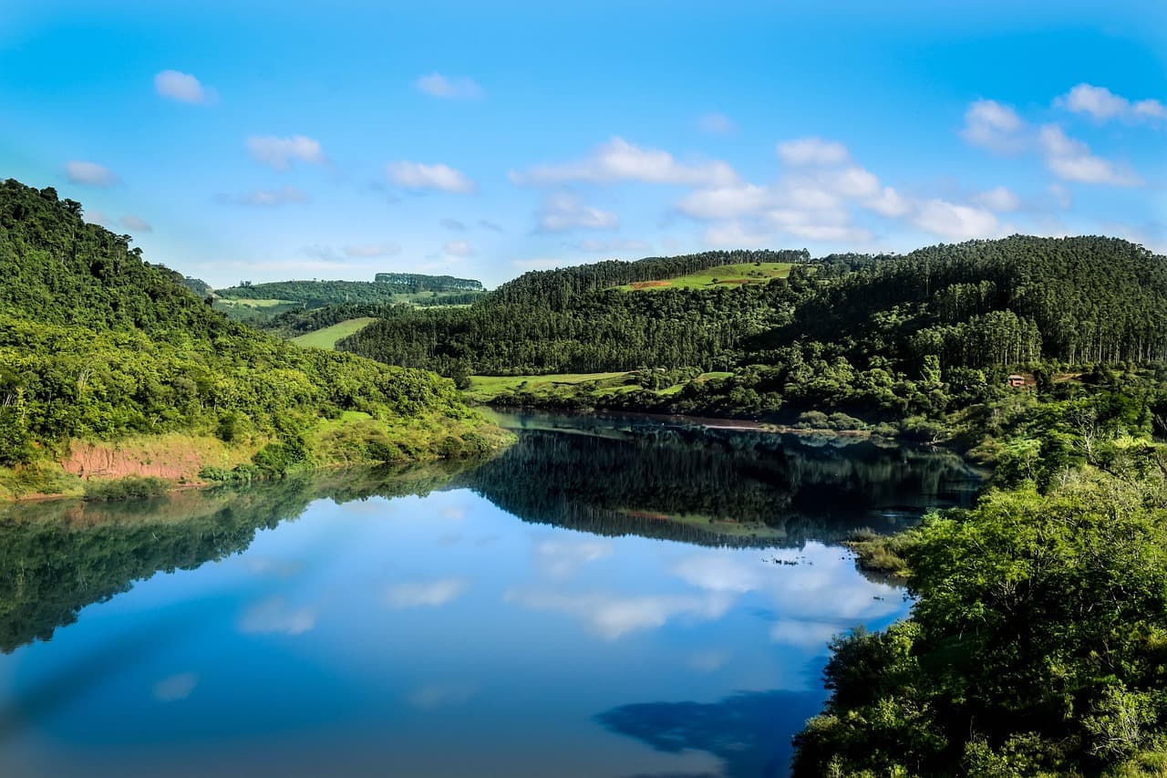 Colinas, río y árboles reflejados en el agua, en el chat de Itá