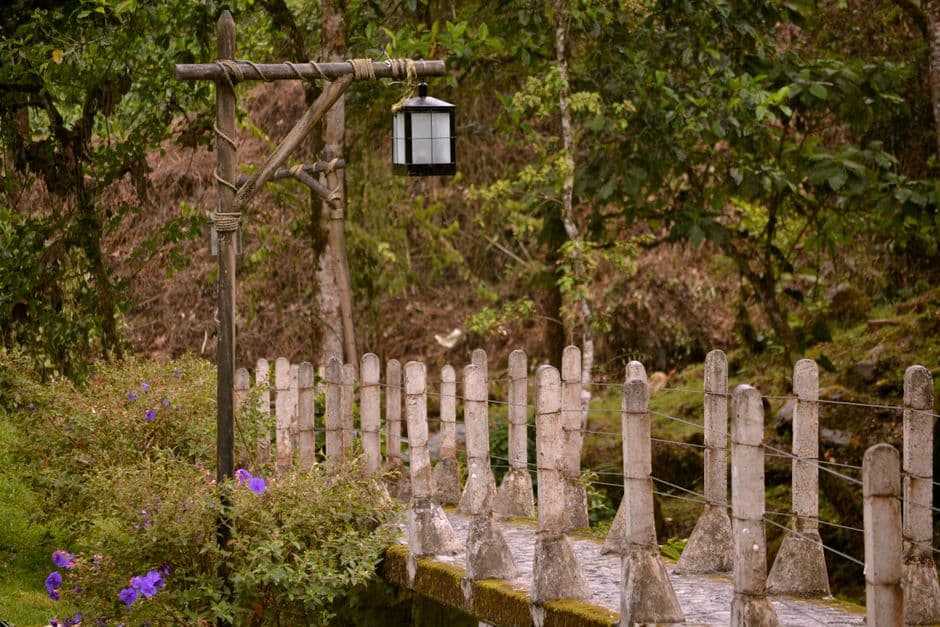 Farola negra colgada de un poste de madera junto a un puente, en el chat de Santa Rosa de Cabal