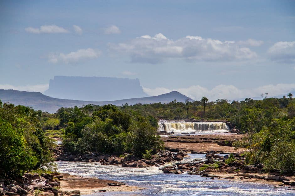 Panorama de un río con cascada y una montaña de cima plana a lo lejos, en el chat de Bruzual