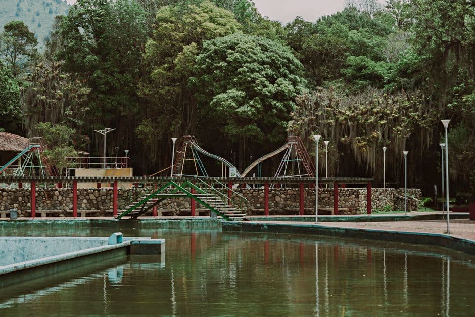 Zona de juegos en un parque verde con un estanque, en el chat de Los Salias