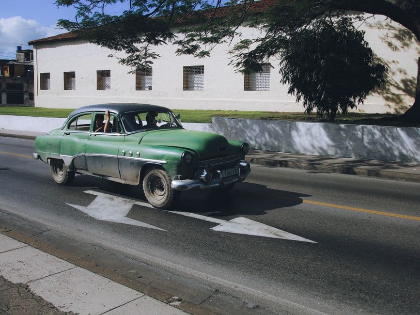 Coche clásico verde en la carretera, en el chat de Banes