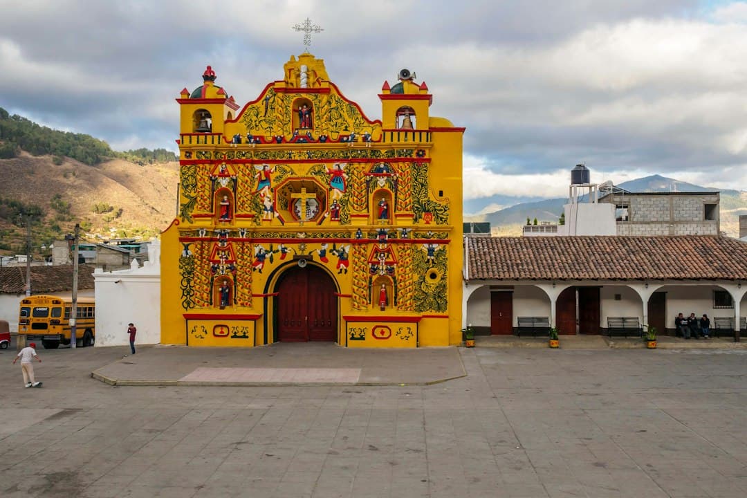 Edificio amarillo y rojo con un reloj en la fachada, en el chat de San Juan Ostuncalco