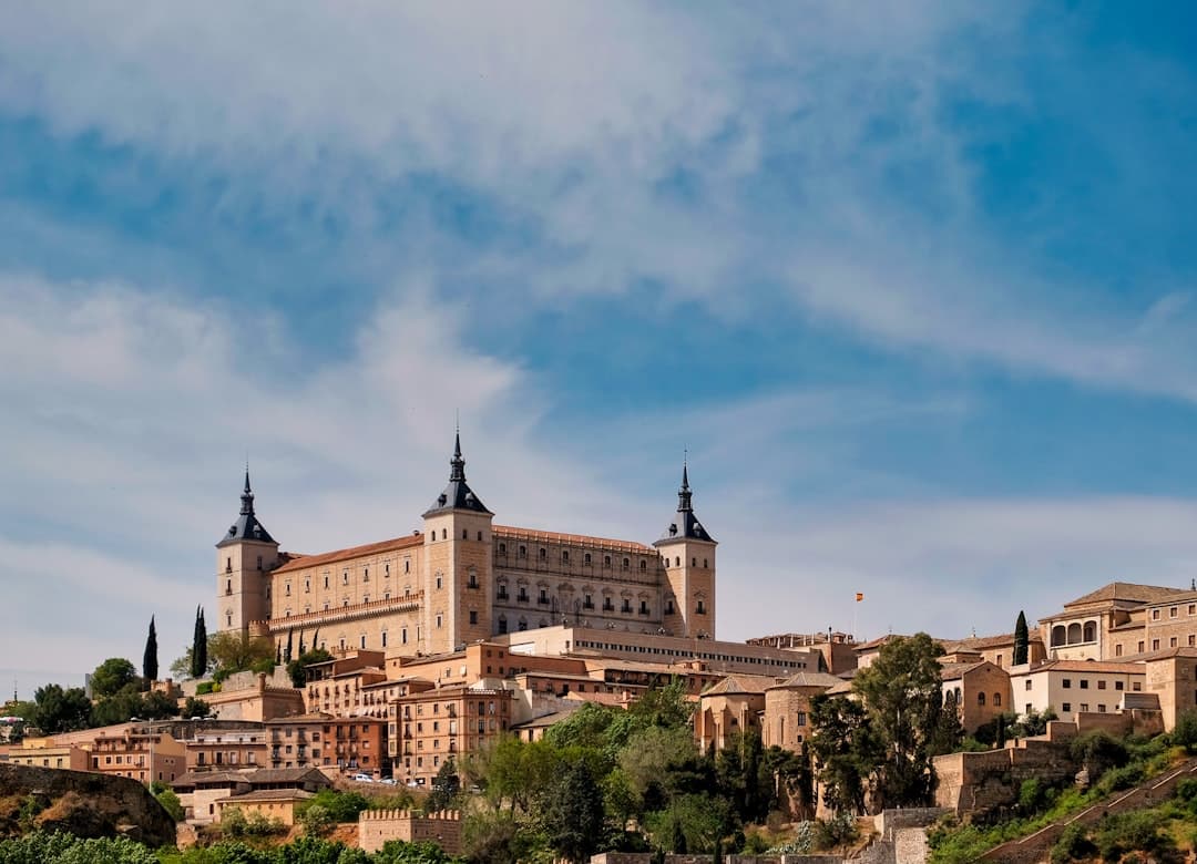Edificio de concreto marrón y blanco bajo cielo azul, en la sala de chat de Toledo