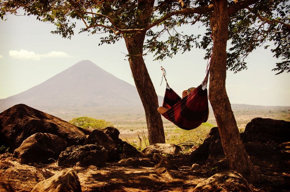 Persona en hamaca negra junto a montaña bajo cielo nublado, en el chat de Jinotega