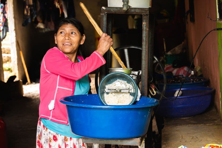 Mujer moliendo maíz en el interior de una casa, en el chat de Chajul