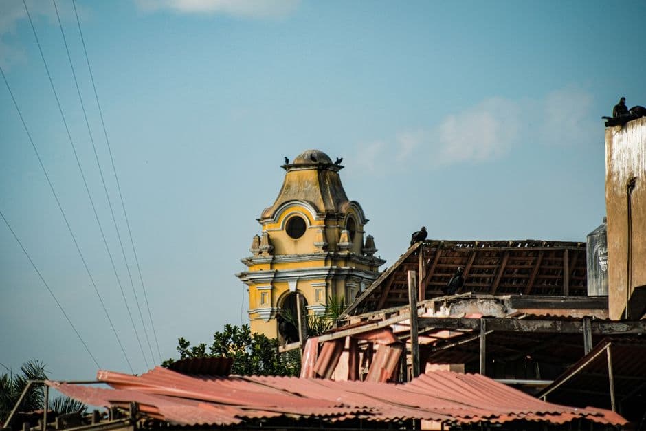 Torre del reloj amarilla con aves posadas, en el chat de Tucurú