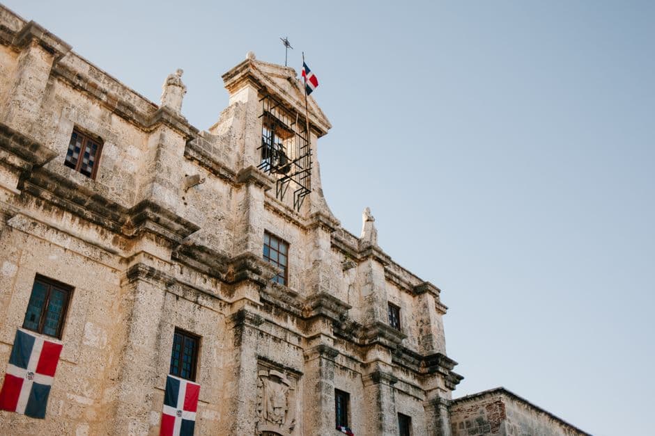 Fachada de edificio viejo con bandera dominicana, en el chat de Santo Domingo Norte