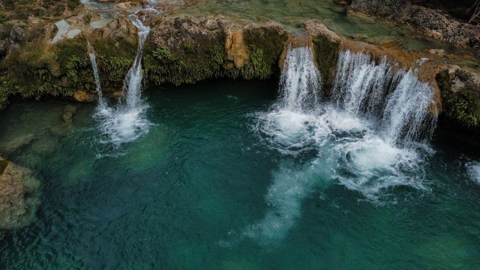 Cascada rodeada de vegetación exuberante y rocas, en el chat de Bajos de Haina