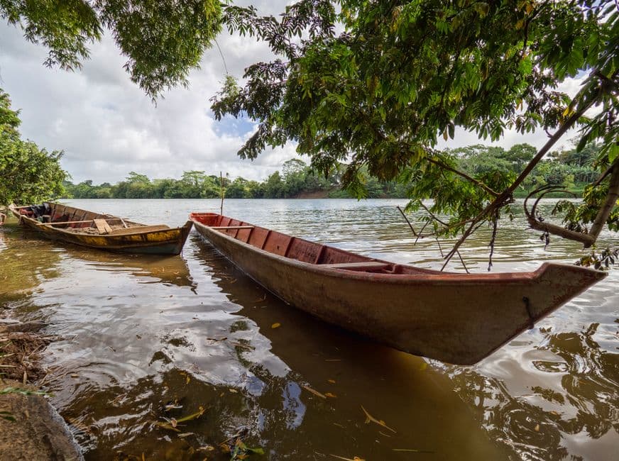 Barcas de madera marrón junto a la orilla de un río, en el chat de El Cuá
