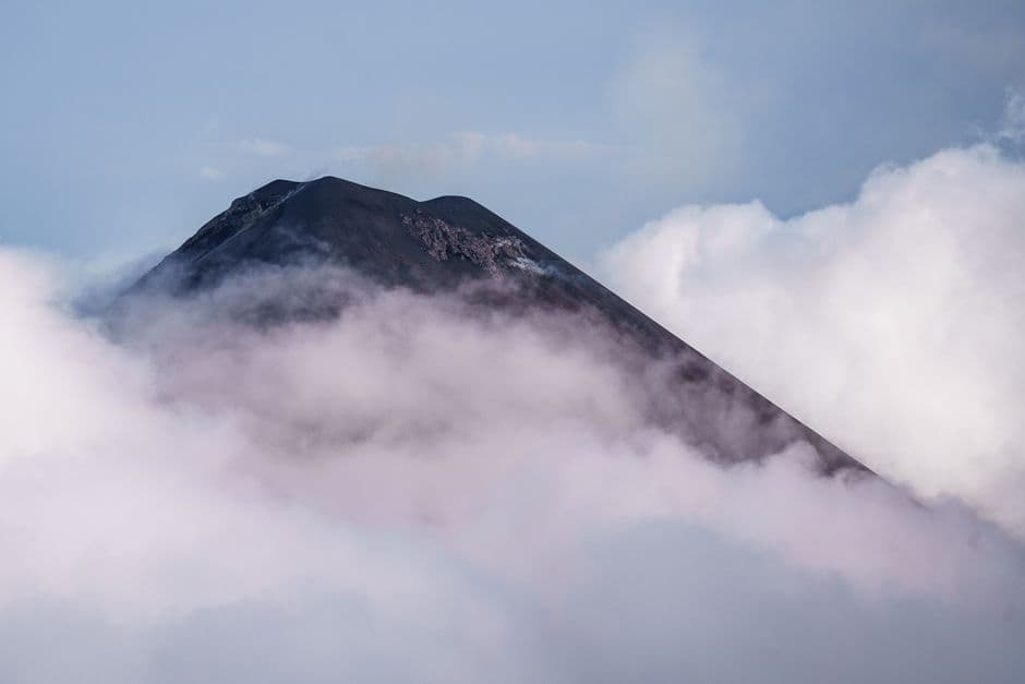 Montaña cubierta de nubes con un pequeño volcán al fondo, en el chat de Patulul