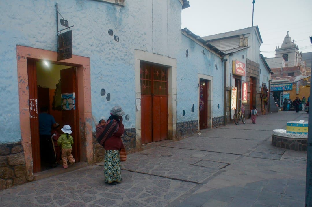 Gente caminando por una calle con edificios azul claro, en el chat de Monsefú