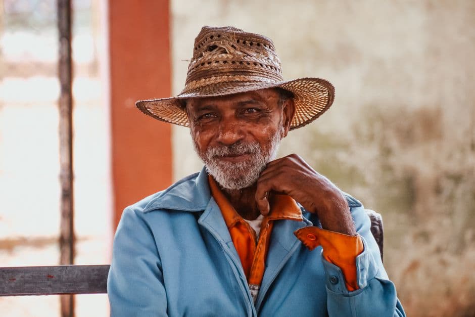 Hombre mayor sonriente con sombrero de paja en una calle soleada, en el chat de Sandino