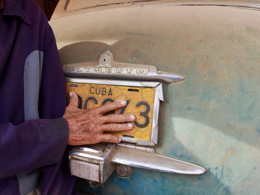 Mano de un anciano tocando la matrícula de un coche, en el chat de Guamá