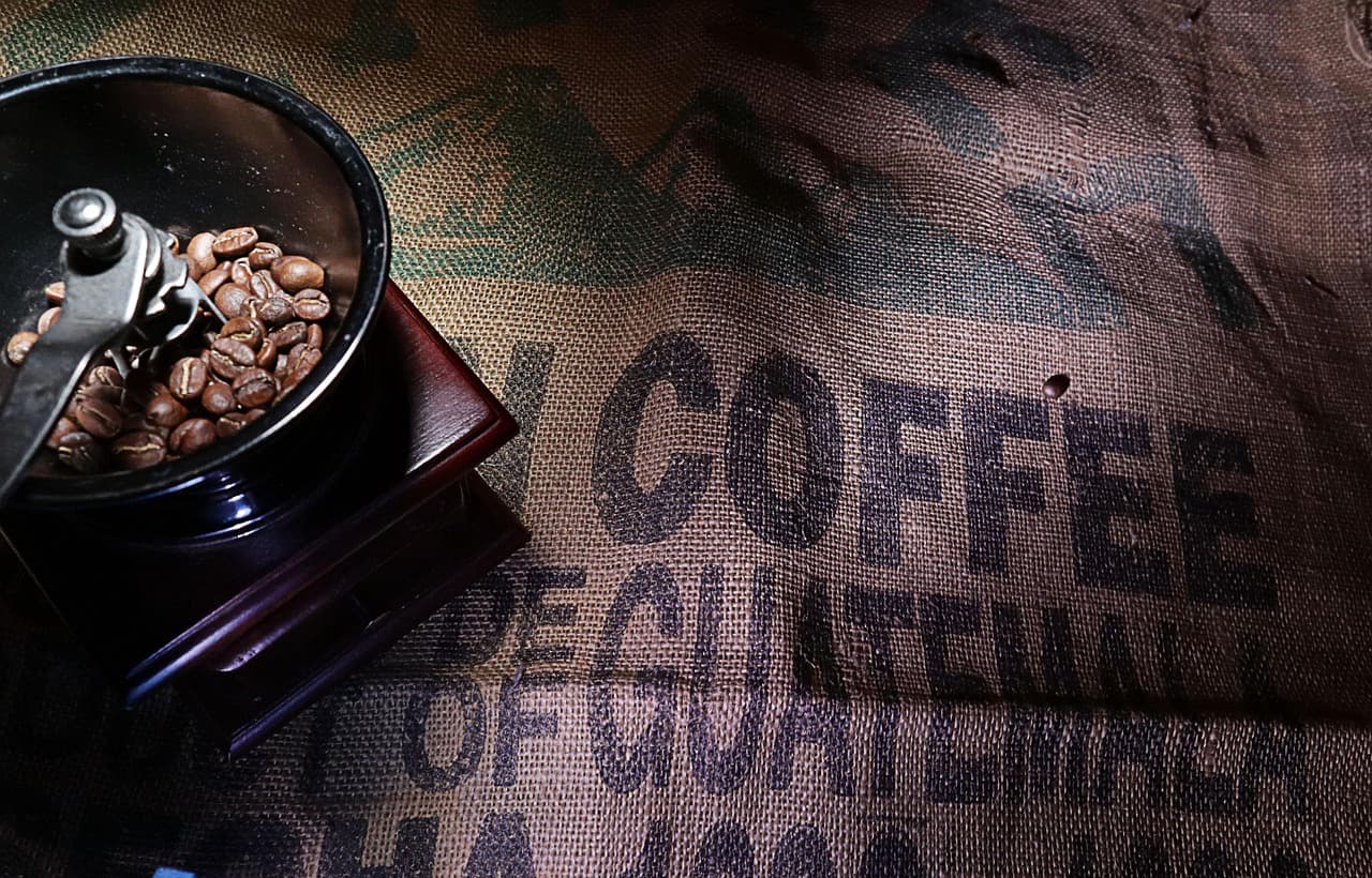 Taza de café humeante sobre granos tostados, evocando aroma, en la sala de chat de Jalpatagua