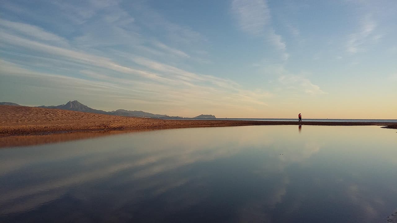 Lago sereno con vegetación exuberante y cielo despejado, en el chat de San Juan Ixcoy