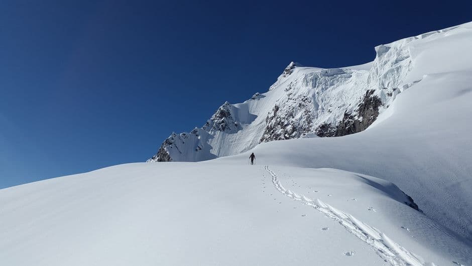 Hombre caminando por una montaña nevada de día, en el chat de Monte Patria
