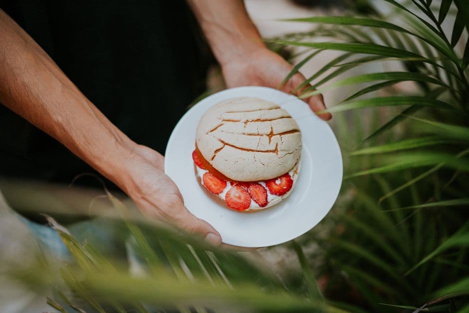 Una persona sosteniendo un pan de concha en un plato blanco, en el chat de Dulce Nombre de Culmí