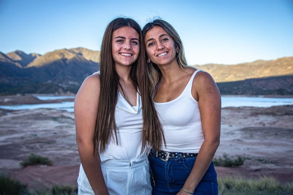 Dos mujeres sonríen al aire libre con montañas, en la sala de chat de Dos Hermanas