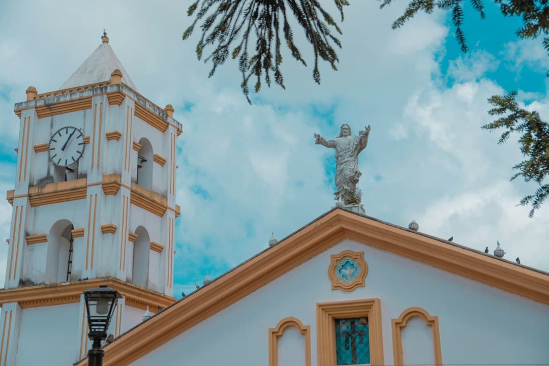 Iglesia con torre de reloj y una estatua en lo alto, en el chat de Jesús de Otoro