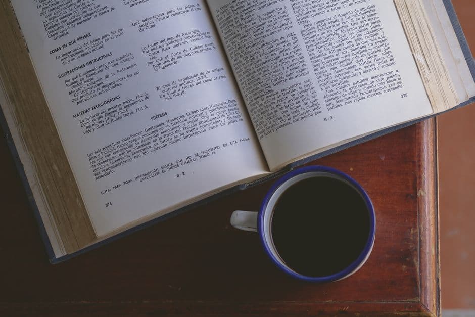 Libro abierto junto a una taza de café sobre una superficie de madera, en el chat de Punceres