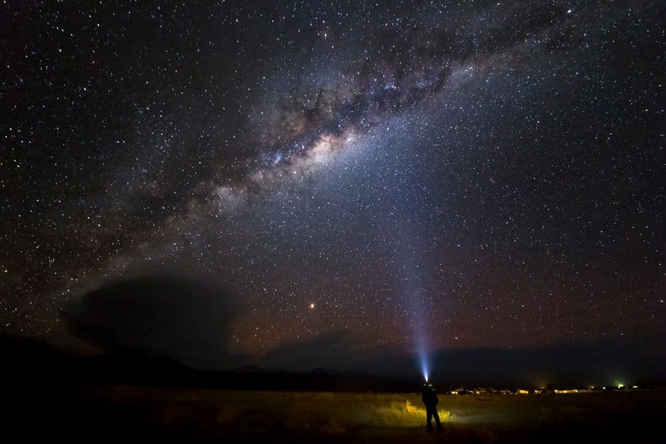 Persona con una linterna bajo un cielo estrellado, en el chat de San Pedro