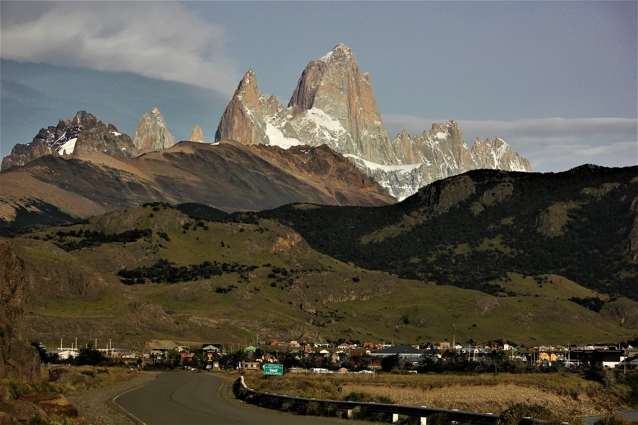 Carretera asfaltada que cruza un pueblo con montañas al fondo, en el chat de Arrecifes