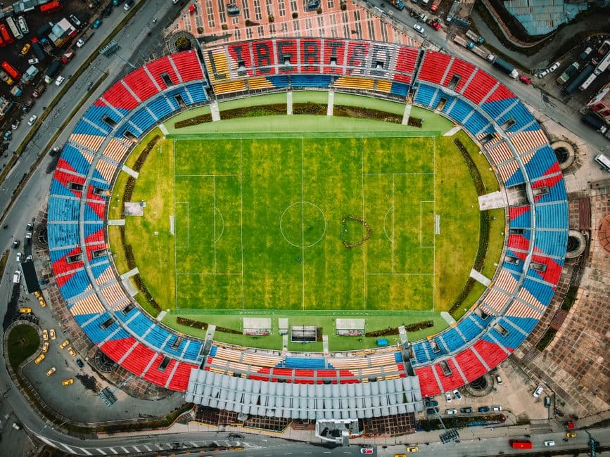 Vista aérea de un campo de fútbol verde, rodeado de árboles, en el chat de Pasto