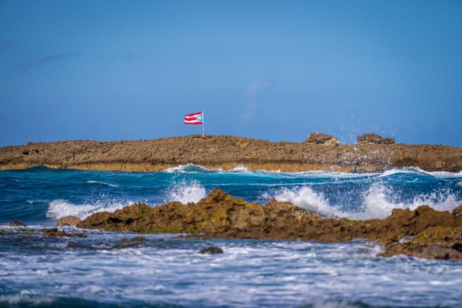 Bandera de Puerto Rico sobre las rocas de la orilla del mar, en el chat de Aibonito