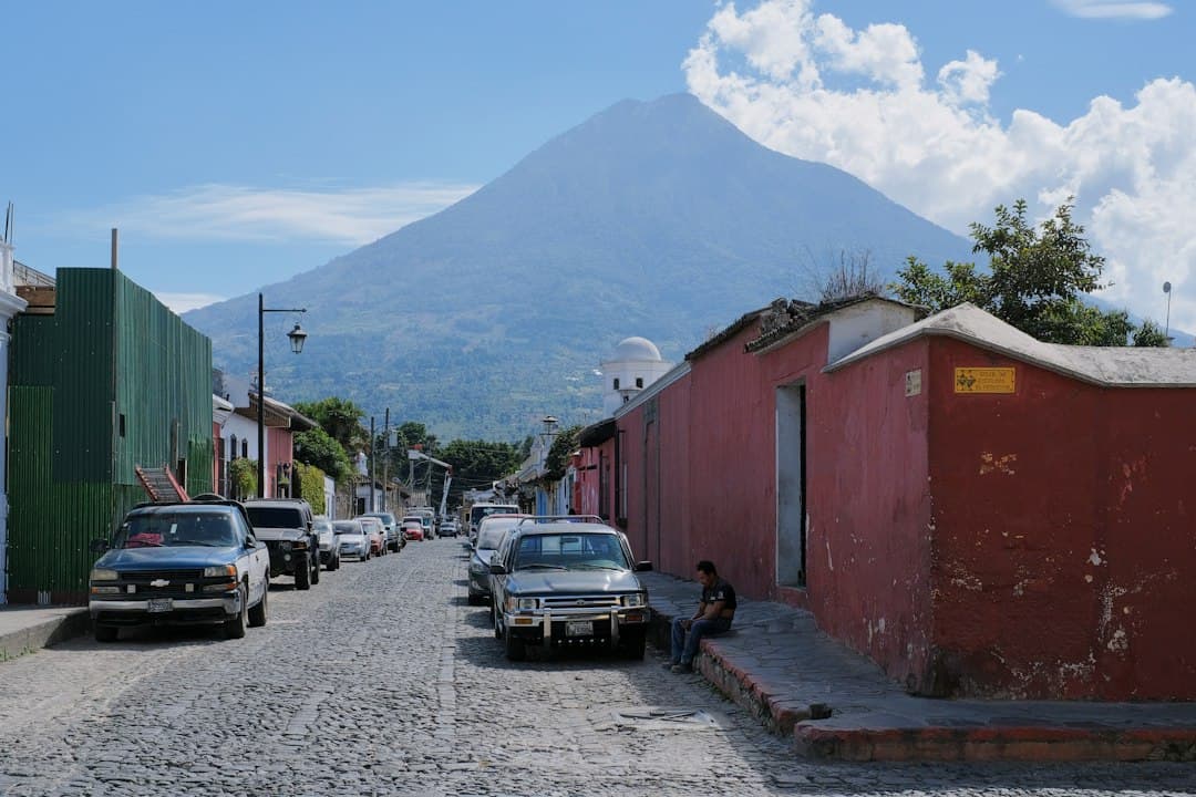 Calle con coches aparcados a ambos lados y una montaña al fondo, en el chat de Tamahú