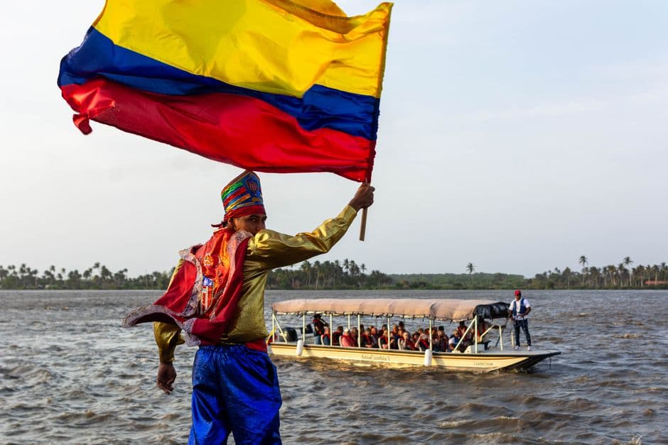 Desfile colorido con la bandera de Colombia junto al río, en el chat de Cogua