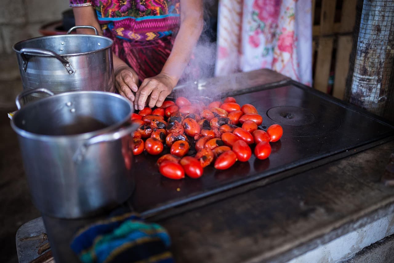 Mujer cocina tortillas al fuego de leña en aldea, en la sala de chat de Quesada